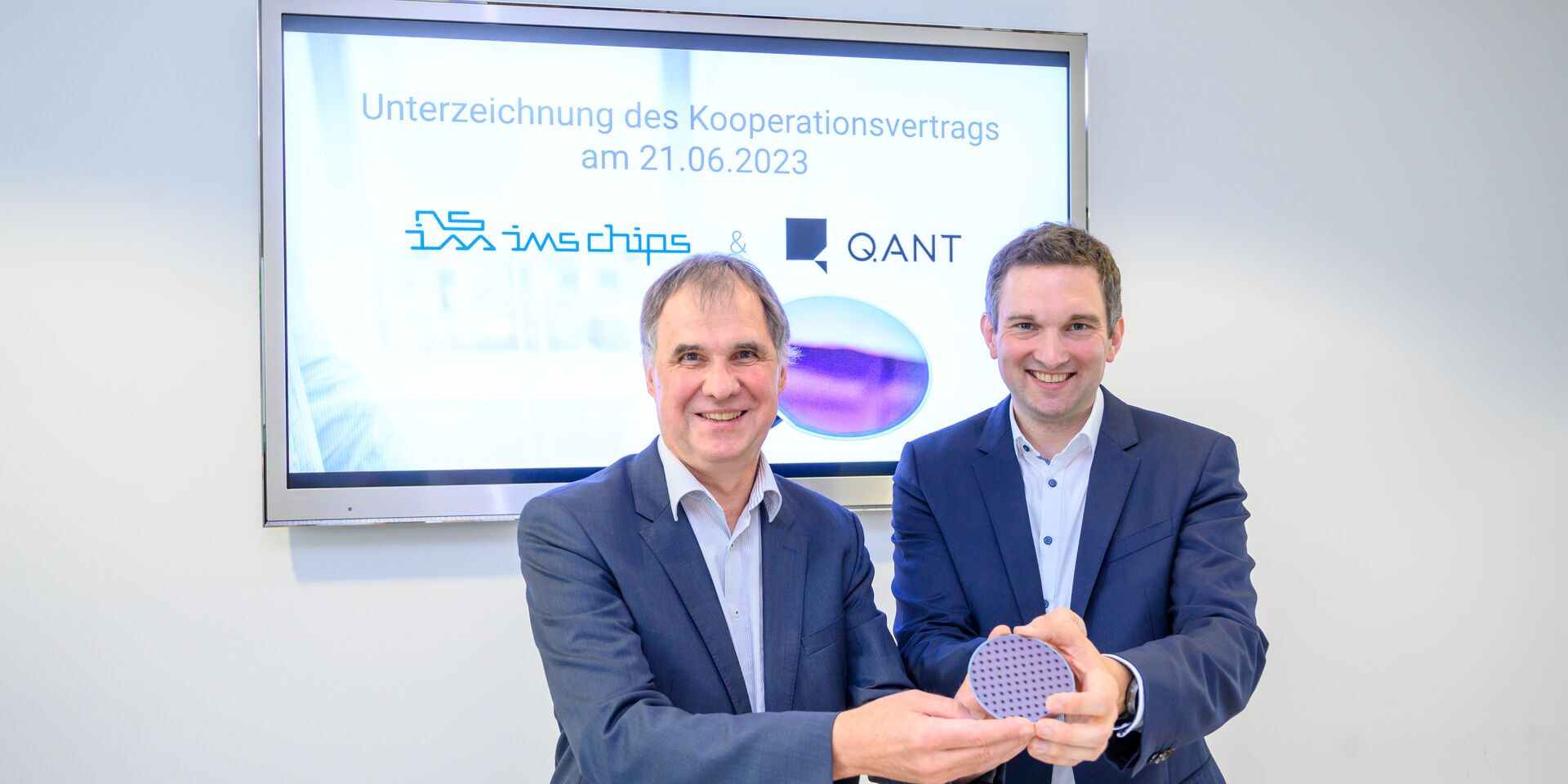 Ein Foto von Prof. Dr. Joachim Burghartz und Michael Förtsch, die vor einem Bildschirm gemeinsam einen Wafer halten.